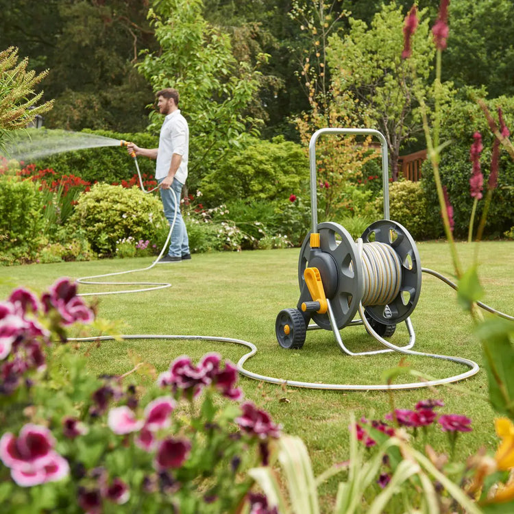 Man watering his garden and plants using a Hozelock hose pipe available from Davies DIY & Builders Merchants